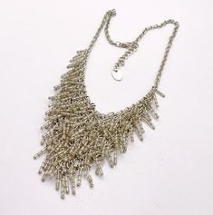 A super fun vintage bib necklace with beaded fringe. The necklace is about 15 to 17 inches long.  Silvertone metal.  Chain.  V shaped chaine maille style bib, about 4 1/2 inches wide by about 2 3/6 inches long.  Clear bugle beaded fringe for great movement.  Lobster claw clasp.  Blank hang tag!  Good vintage condition, some wear to the surface.   You can find more vintage beaded necklaces here: https://www.etsy.com/shop/OtterCatHaus/search?search_query=beaded+necklace&order=date_desc&view_type=gallery&ref=shop_search Please convo with any questions.  I combine shipping and refund overages of more than fifty cents.  Thanks for visiting today! Vintage Beads Necklace, Bib Necklaces, Bugle Beads, Beaded Fringe, Beaded Necklaces, Bib Necklace, Hang Tags, Metal Chain, V Shape