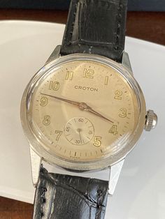 Excellent working and good cosmetic condition. New high dome crystal. Newly added replacement vintage stainless steel case. Comes with a black 18mm genuine leather band. Case size 32mm. 90 day money back guarantee, no questions asked, and 2-year warranty on our service. Movement can be displayed if desired. We still have the one original case and crown in case you are interested to see what it originally looked like. I have also added extra photos on our Instagram page. Vintage Chronometer Watch As A Gift, Vintage Black Watch Accessories With Polished Finish, Black Vintage Watch Accessories With Polished Finish, Vintage Business Watch With Metal Dial, Vintage Black Watch With Metal Dial, Vintage Black Watch With Polished Finish, Vintage Black Collectible Watch, 1940’s Watches, Wristwatch Men