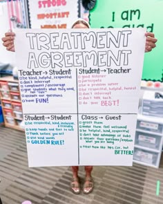 a person holding up a sign that says treatment agreement and student - teacher rules in front of them