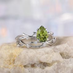 a green ring sitting on top of a rock next to a white crystal stone slab