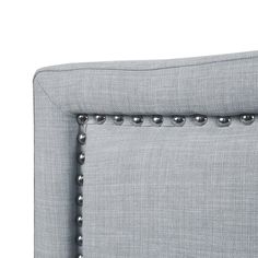 an upholstered headboard with metal studding on the arms and backrests