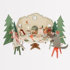 paper cut out of mice sitting at a table in front of a small house with trees