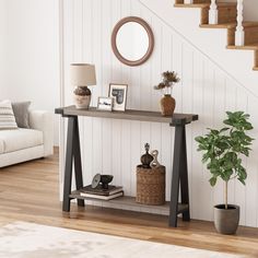 a living room with a couch, table and mirror on the wall next to stairs