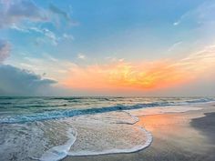 the sun is setting over the ocean with waves coming in to shore and blue sky