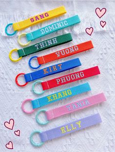 six different colored key chains on a white table cloth with hearts and words written on them