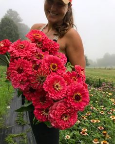 a woman holding a bunch of red flowers in her hands on a foggy day