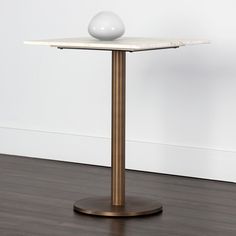 a white ball sitting on top of a wooden table next to a wall and hardwood floor