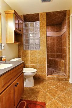 a bathroom with wooden cabinets and tile flooring is shown in this image, there is a shower stall next to the toilet