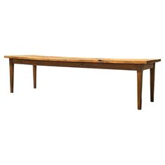 a long wooden table sitting on top of a white floor next to a wall with an open drawer