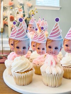 three babys wearing birthday hats sitting in front of cupcakes