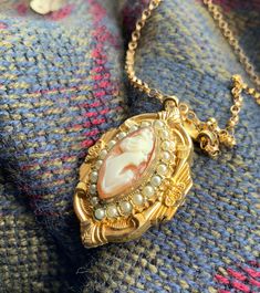 This vintage locket pendant is 10 KT Gold Filled with pearl seeds.  The cameo locket measures 1 1/4 inches long x 3/4 of an inch wide.  The chain is 18 inches long.  This a beautiful piece.  It was stored in a case in an antique store for many years.  It has not been worn.  It is very good condition.  🙂 Cameo Locket, Reza Pahlavi, Vintage Locket, Vintage Lockets, Antique Store, Antique Stores, Pendant Necklaces, Locket, Gold Filled