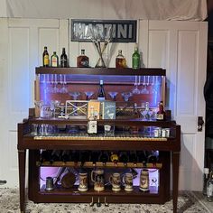 an old piano with wine glasses and bottles sitting on it's stand in front of a white wall