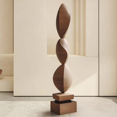 a tall wooden sculpture sitting on top of a white floor next to a chair and table