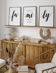 two framed pictures on the wall above a wooden cabinet in a living room with wicker furniture