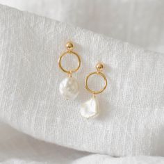 These earrings feature a simple gold circle finished with a dangling freshwater pearl. Made of 14K gold filled materials and genuine freshwater pearls, these earrings are tarnish-resistant, water-resistant, and hypoallergenic. Earring length measures approximately 1.5 inches long. --------------------♥ PROMOS ♥-------------------- Want 10% off? Join the mailing list by visiting http://bit.ly/vedern . Just leave me a note at checkout if you have any problems applying discount codes. ------------- Gold And White Earrings, Wedding Pearl Drop Earrings, Handmade Pearl Hoop Earrings For Weddings, White Pearl Charm Hoop Earrings For Wedding, White Hoop Earrings With Pearl Charm For Wedding, Pearl White Single Earring Jewelry Gift, Pearl White Single Earring As Gift, Minimalist Dangle Bridal Earrings As Gift, Anniversary Pearl Charm Dangle Earrings