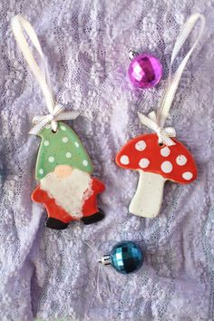 two christmas ornaments are sitting on a lace tablecloth