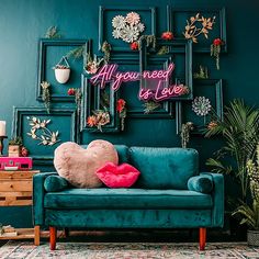 a blue couch with a pink heart pillow on it in front of a green wall