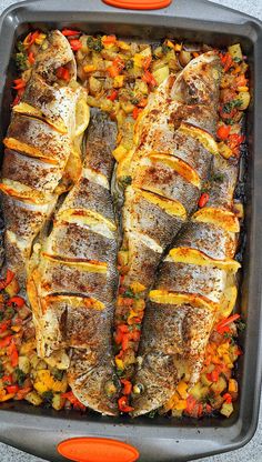 fish in a pan with carrots, potatoes and broccoli on the side