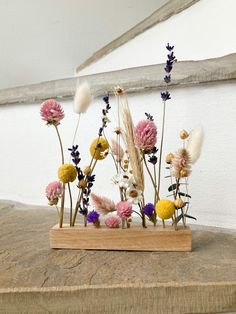 an arrangement of wildflowers and grasses in a wooden vase