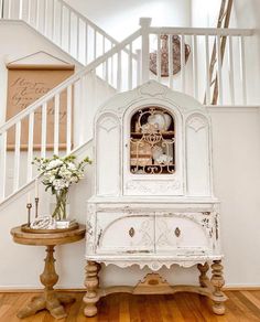 a white cabinet sitting on top of a hard wood floor next to a stair case