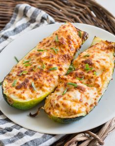 zucchini stuffed with cheese and herbs on a white plate next to a wicker basket