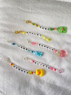 four personalized keychains are arranged on a white sheet with the names of three different children's name tags