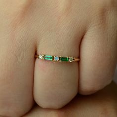 a woman's hand with a gold band and green stone ring on it,