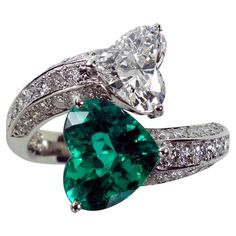 the Epitome of Love: Platinum Heart-Shaped Emerald and Diamond Ring! Indulge in the beauty of everlasting love with our Platinum Ring, featuring a stunning 1.70ct Heart-Shaped Emerald and a 1.011ct Heart-Shaped Diamond. This exquisite piece is adorned with a white diamond shank totaling 0.50ct, adding brilliance to its already enchanting design. Ring Features: Metal: Luxurious Platinum - A symbol of enduring love Gemstones: Heart-Shaped Emerald (1.70ct, G.I.A. clarity enhanced F1) and Heart-Shaped Diamond (1.011ct, G SI1 certified by C.G.L.) Shank Diamonds: 0.50ct white diamonds for added sparkle Why Choose Our Heart-Shaped Emerald and Diamond Ring? Symbol of Love: The heart-shaped design signifies love and commitment, creating a meaningful piece. Unmatched Brilliance: The combination of t Heart Shape Emerald Ring, Heart Shape Ring, Emerald And Diamond Ring, Bypass Ring, Heart Shaped Rings, Heart Shaped Diamond, Everlasting Love, Fine Jewels, Platinum Ring