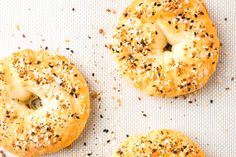 three bagels with sesame seeds and poppy seeds on top are sitting on a baking sheet