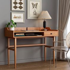 a desk with a lamp and pictures on the wall above it in a living room