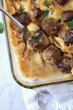 a casserole dish with meatballs and noodles in gravy, garnished with parsley