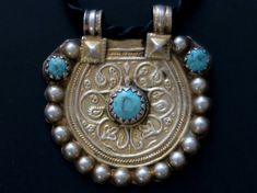 This large traditional pendant was handcrafted during the mid-1900's in Old India. It is vintage tribal jewelry - not a new reproduction. MEASUREMENTS (1 inch = 2.54 cm): Pendant dimensions = 2-1/4 inches long x 2 inches wide Free neck-cord length = 18 inches Weigh = 0.9 oz Shipping Weight = 7 oz TM Image Library = 5-11-2021 The design on this unusual vintage pendant has an elevated border and raised-patterns of flowers with leafy tendrils. 3 natural turquoise beads add color and dimension to th Old India, Traditional Pendant, Mount Dora, Indian Jewelry Earrings, Turquoise And Gold, Vintage Pendant, Gold Gilding, Natural Turquoise, Lady Dior Bag