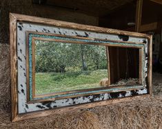 a cow in a barn looking at its reflection in a mirror that is hanging on the wall