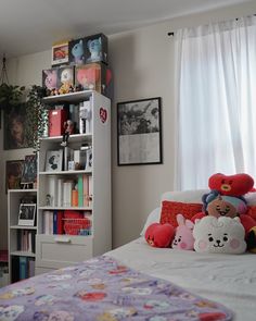 a bed with stuffed animals on top of it in front of a book shelf filled with books