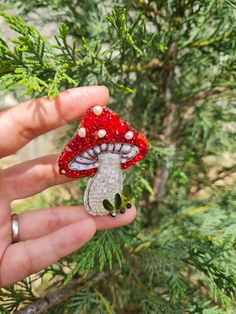 a hand holding a tiny red mushroom ornament