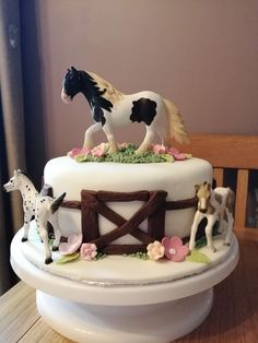 a cake decorated with figurines of horses on top of a wooden table next to a window