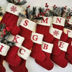 christmas stockings with letters and snowflakes hanging from the top, along with pine branches