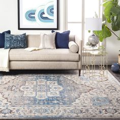 a living room scene with focus on the couch and rug in the foreground as well as an art piece