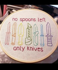 there is a cross stitch pattern on the hoop with scissors and knifes in it