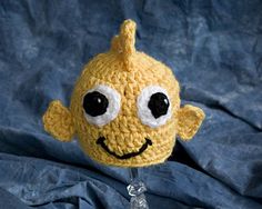 a crocheted yellow stuffed toy with big eyes and a smile on it's face