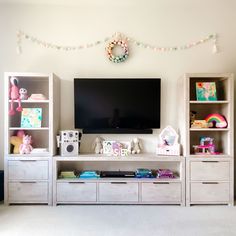 the entertainment center is decorated in pastel colors and features toys, bookshelves, and a flat screen tv