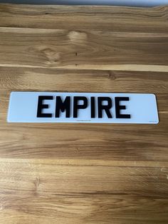 an empre license plate sitting on top of a wooden table with the word empire printed on it