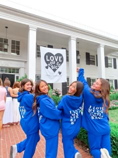 three girls in blue sweat suits holding up a love you sign