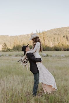 a man and woman are standing in the grass with their arms around each other as they kiss