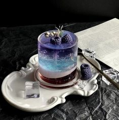 a blue and white drink with berries on top sits on a tray next to a piece of paper