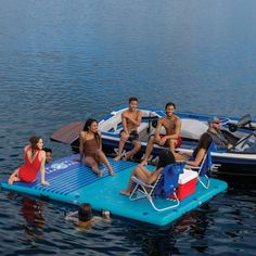 a group of people sitting on top of a blue raft in the water next to a boat