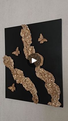 a piece of art that is on the wall with some butterflies flying around it,