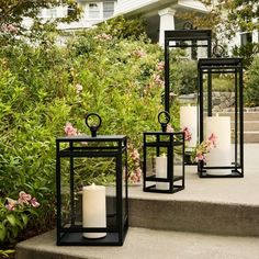 three black lanterns sitting on the steps in front of some bushes