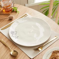 there is a white plate on the table with gold utensils next to it