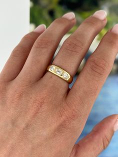 a woman's hand wearing a gold ring with two small diamonds on the band